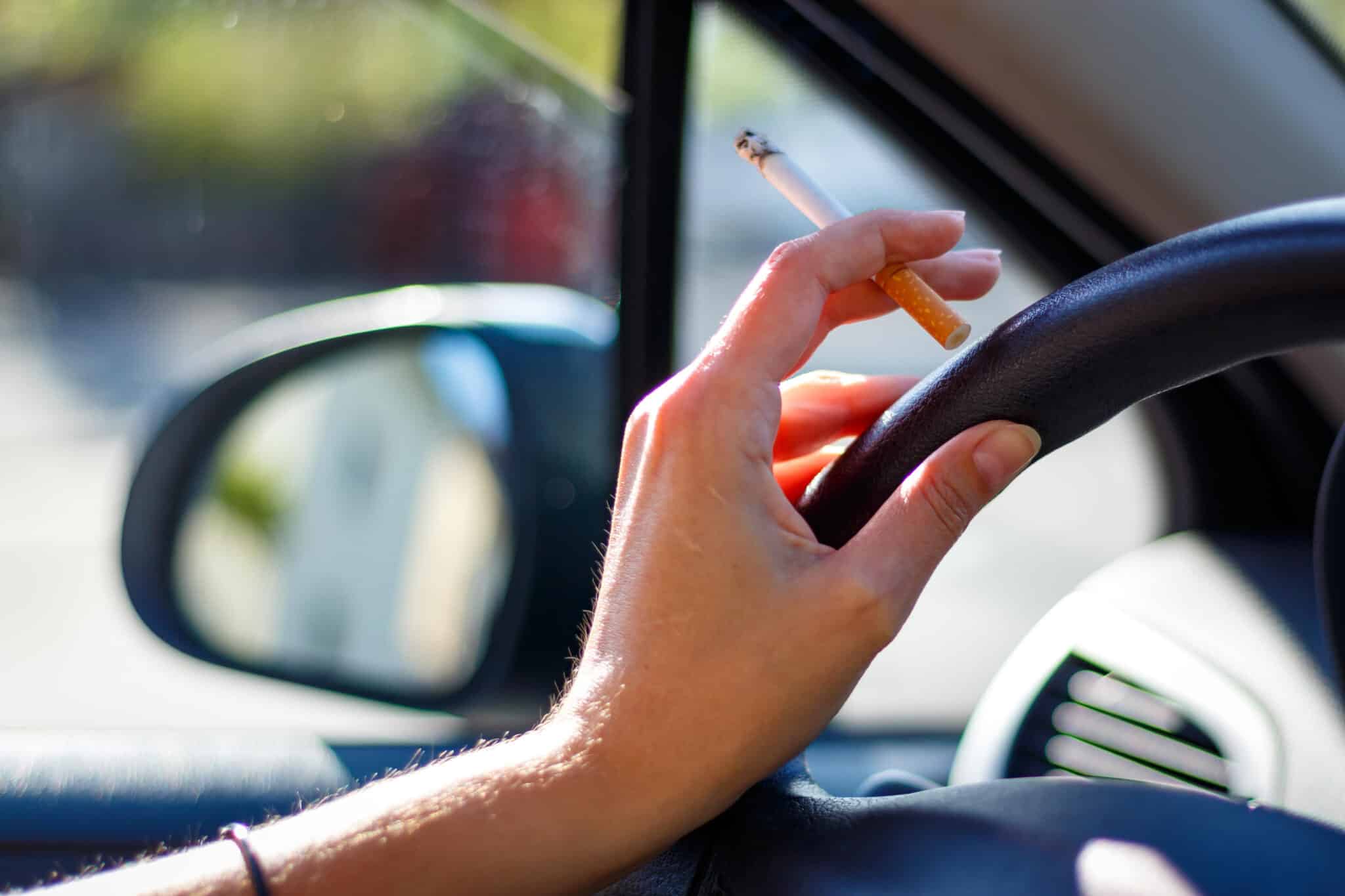Woman smoking a cigarette at the wheel of a car